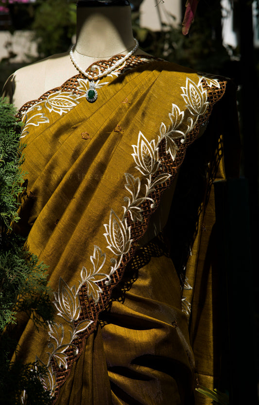 Mustard yellow saree with intricate white and brown patterns on a mannequin.