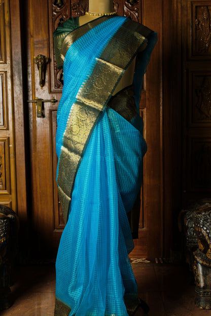 Blue saree with gold border on a mannequin against a wooden background