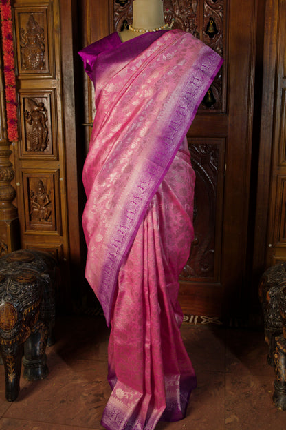 Pink saree with purple border on a mannequin against a wooden carved backdrop
