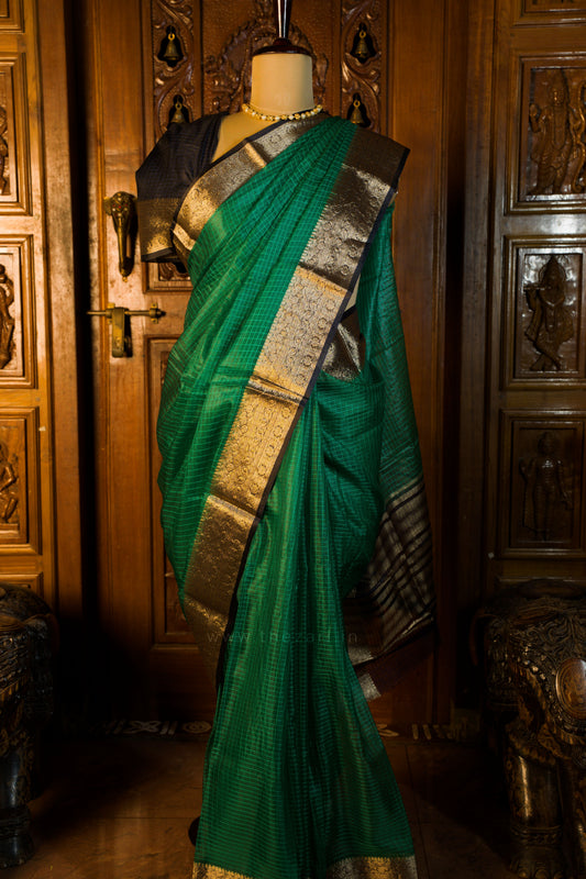 Green saree with gold border on a mannequin against a wooden background