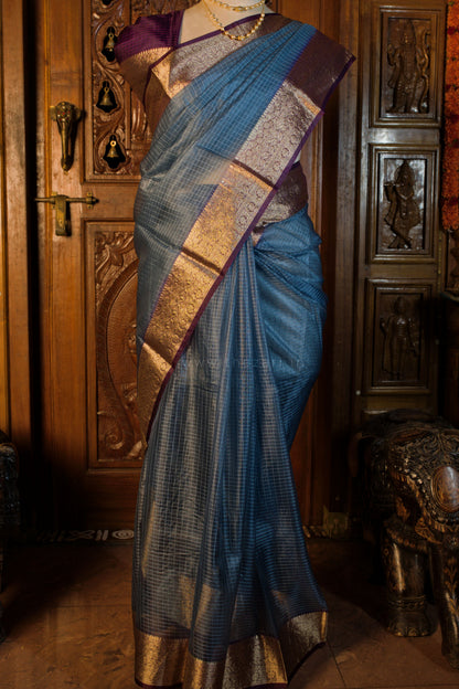 Blue saree with gold patterns draped over a mannequin against a wooden background