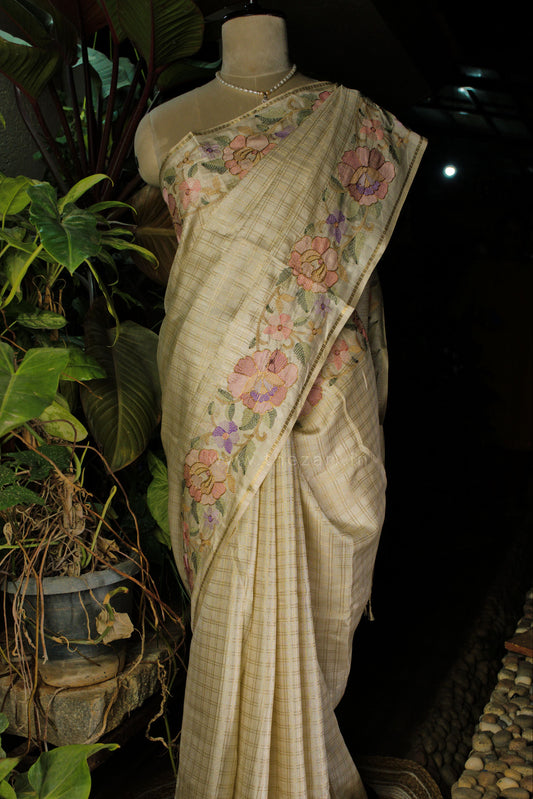 Saree with floral patterns on a mannequin against a dark background with plants.